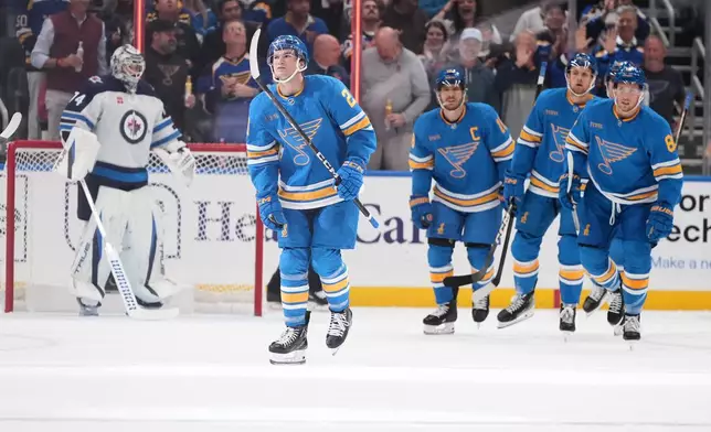 St. Louis Blues' Jimmy Snuggerud, second from left, skates off the ice after scoring past Winnipeg Jets goaltender Stuart Skinner (74) during the first period of an NHL hockey game Tuesday, Oct. 20, 2026, in St. Louis. (AP Photo/Jeff Roberson)