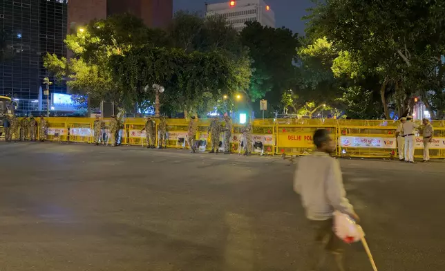 A man walks past security officers near a barricade in the heart of New Delhi, India, Monday, Oct. 12, 2026. (AP Photo/Yirmiyan Arthur)