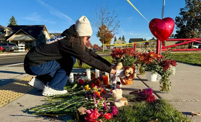 A person places flowers at a makeshift memorial on the other side of Silver Rail Elementary School in Bend, Ore., on Friday, Oct. 16, 2026, a day after a deadly shooting. (AP Photo/Haven Daley)