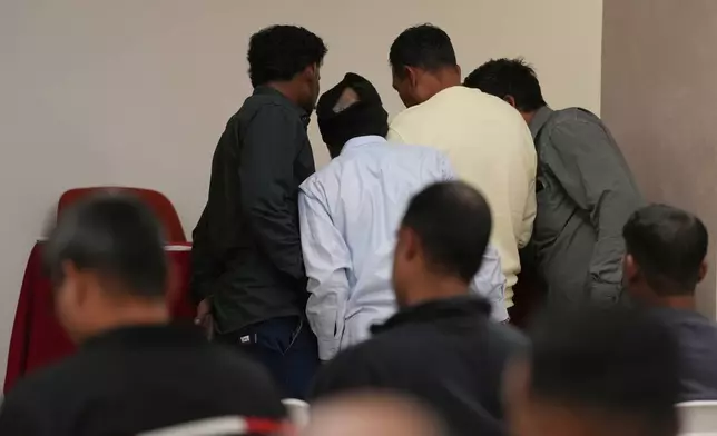 Caddell workers gather in a hotel conference room to wait their turn to sign an agreement for compensation from the U.S. construction company Caddell as part of a settlement into illegal labor practices at a building site for a new U.S. consulate compound in Milan, Italy, Wednesday, Oct. 7, 2026. (AP Photo/Luca Bruno)