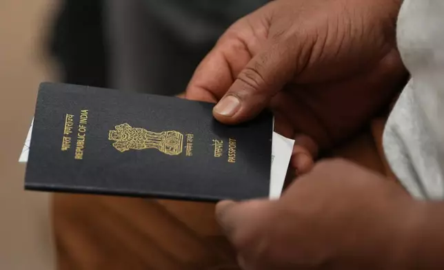 A worker holds his passport in a hotel conference room as he waits his turn to sign an agreement for compensation from the U.S. construction company Caddell as part of a settlement into illegal labor practices at a building site for a new U.S. consulate compound in Milan, Italy, Wednesday, Oct. 7, 2026. (AP Photo/Luca Bruno)