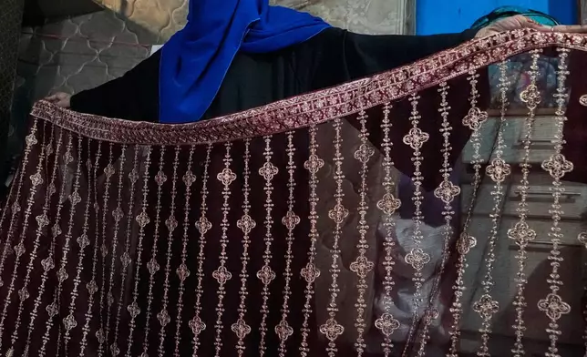Siddiqui, who The Associated Press is identifying by surname only because of potential retaliation from her employer, shows her embroidery work that she does for extra income in Karachi, Pakistan, Sunday, Oct. 4, 2026. (AP Photo/Anjum Naveed)