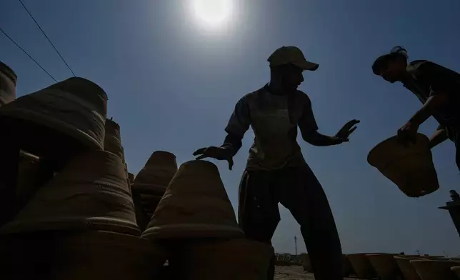 Workers arrange pots at a clay factory on a hot day in Karachi, Pakistan, Saturday, Oct. 3, 2026. (AP Photo/Anjum Naveed)