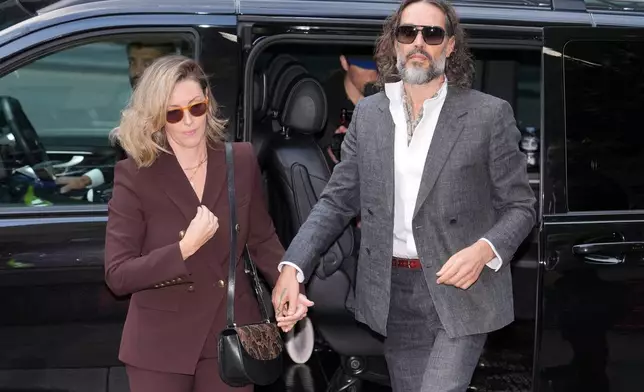 Comedian and actor Russell Brand, accompanied by his wife Laura Brand, arrives at Southwark Crown Court where he is charged with counts of rape and sexual assault against six women, which he has denied, in London, Monday, Oct. 12, 2026.(AP Photo/Kin Cheung)