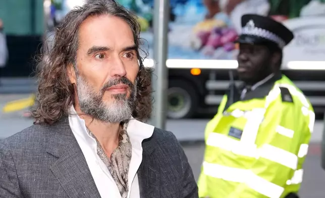Comedian and actor Russell Brand arrives at Southwark Crown Court where he is charged with counts of rape and sexual assault against six women, which he has denied, in London, Monday, Oct. 12, 2026.(AP Photo/Kin Cheung)