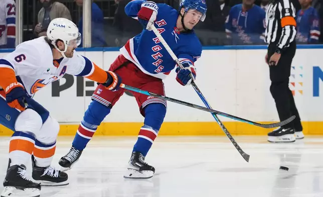 New York Rangers' Alexis Lafrenière, right, shoots the puck past New York Islanders' Ryan Pulock (6) for a goal during the second period of an NHL hockey game Tuesday, Oct. 6, 2026, in New York. (AP Photo/Frank Franklin II)