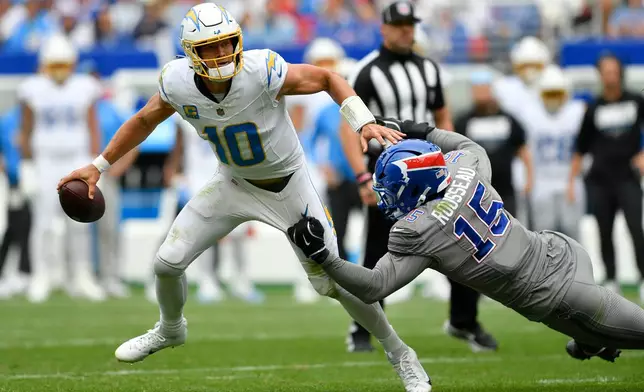 Los Angeles Chargers quarterback Justin Herbert (10) runs from Buffalo Bills linebacker Greg Rousseau (15) during the second half of an NFL football game, Sunday, Sept. 27, 2026, in Orchard Park, N.Y. (AP Photo/Adrian Kraus)