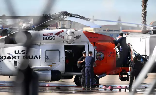 Coast Guardsmen work on a helicopter at Coast Guard Station San Diego on Friday, Oct. 16, 2026. (AP Photo/Denis Poroy)