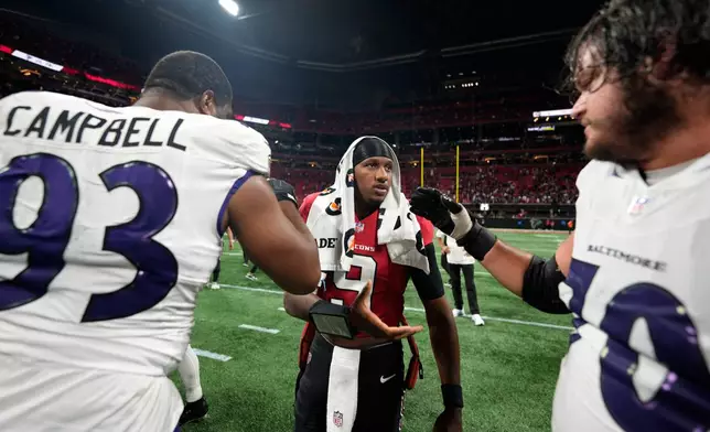 Atlanta Falcons quarterback Michael Penix Jr. (9) talks with Baltimore Ravens defensive end Calais Campbell (93) and offensive tackle Roger Rosengarten (70) after a NFL football game, Sunday, Oct. 11, 2026, in Atlanta. (AP Photo/Mike Stewart)