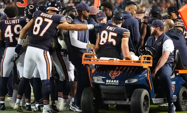 Chicago Bears' Sam Roush (87) reaches out to Cole Kmet (85) as he is carted off the field after suffering an injury on a pass play during the second half of an NFL football game against the New England Patriots in Chicago, Thursday, Oct. 22, 2026. (AP Photo/Nam Y. Huh)