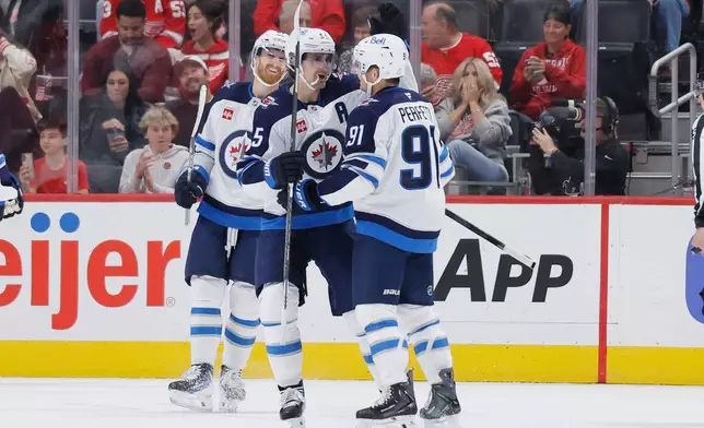 Winnipeg Jets center Cole Perfetti (91) celebrates after his goal against the Detroit Red Wings with left wing Kyle Connor, left, and center Mark Scheifele (55) during the first period of an NHL hockey game Sunday, Oct. 4, 2026, in Detroit. (AP Photo/Duane Burleson)