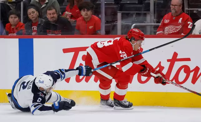 Winnipeg Jets defenseman Dylan DeMelo (2) tries to defend against Detroit Red Wings center Emmitt Finnie (58) during the first period of an NHL hockey game Sunday, Oct. 4, 2026, in Detroit. (AP Photo/Duane Burleson)