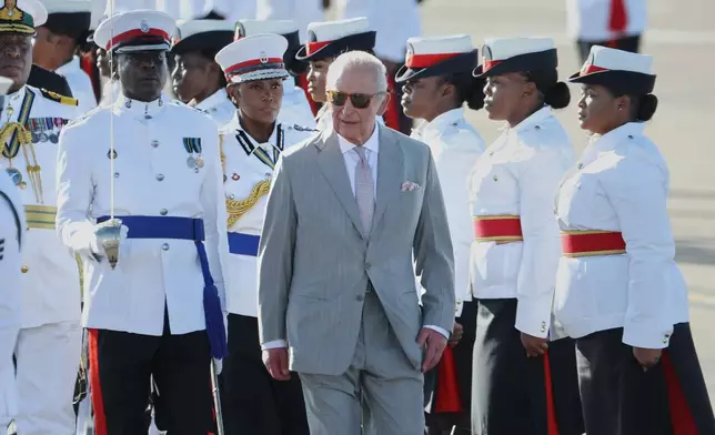 Britain's King Charles III inspects an honor guard after arriving at Lynden Pindling Airport in Nassau, Bahamas, Tuesday, Oct. 27, 2026. (AP Photo/Tim Aylen)