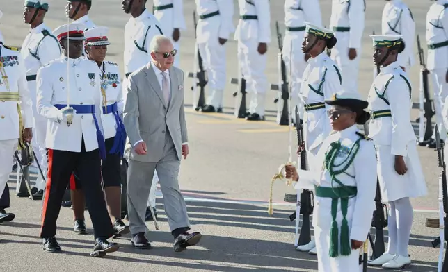 Britain's King Charles III inspects an honor guard at the Lynden Pindling Airport in Nassau, Bahamas, Tuesday, Oct. 27, 2026. (AP Photo/Tim Aylen)