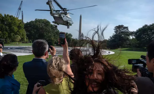 Members of the press watch as Marine One with President Donald Trump aboard lifts off from the South Lawn of the White House, Friday, Oct. 2, 2026, in Washington. (AP Photo/Mark Schiefelbein)