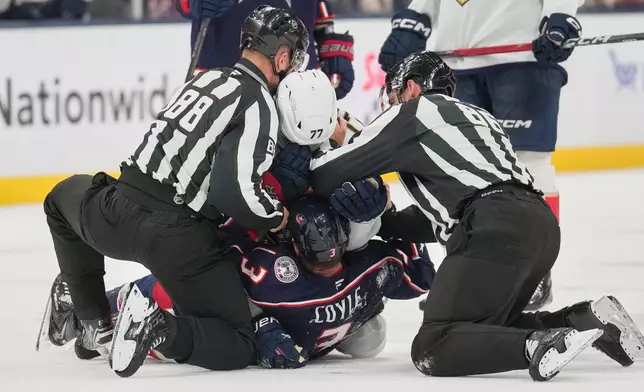 Linesmen separate Florida Panthers defenseman Niko Mikkola (77) and Columbus Blue Jackets center Charlie Coyle (3), who both received roughing penalties, in the second period of an NHL hockey game in Columbus, Ohio, Tuesday, Oct. 13, 2026. (AP Photo/Sue Ogrocki)