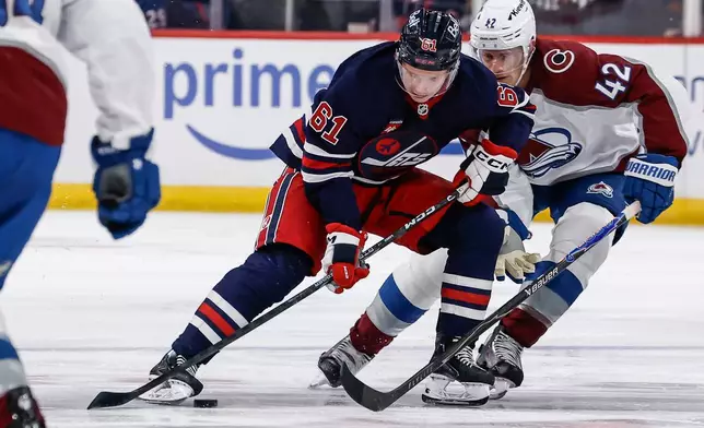 Winnipeg Jets' Viggo Bjorck (61) protects the pucks from Colorado Avalanche's Josh Manson (42) during the second period of an NHL hockey game in Winnipeg, Wednesday, Oct. 7, 2026. (John Woods/The Canadian Press via AP)