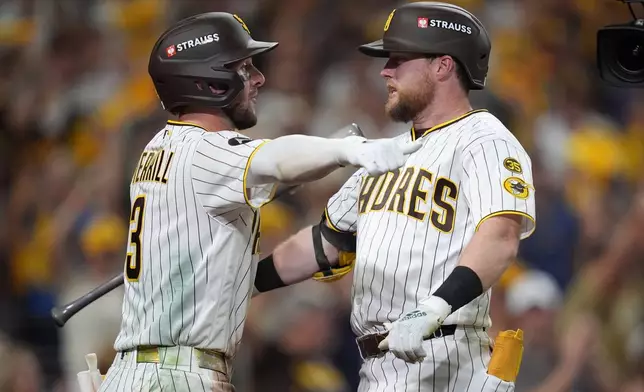 San Diego Padres' Jake Cronenworth, right, is congratulated by teammate Jackson Merrill (3) after hitting a solo home run during the fifth inning in Game 3 of baseball's National League Division Series against the Milwaukee Brewers Tuesday, Oct. 6, 2026, in San Diego. (AP Photo/Gregory Bull)