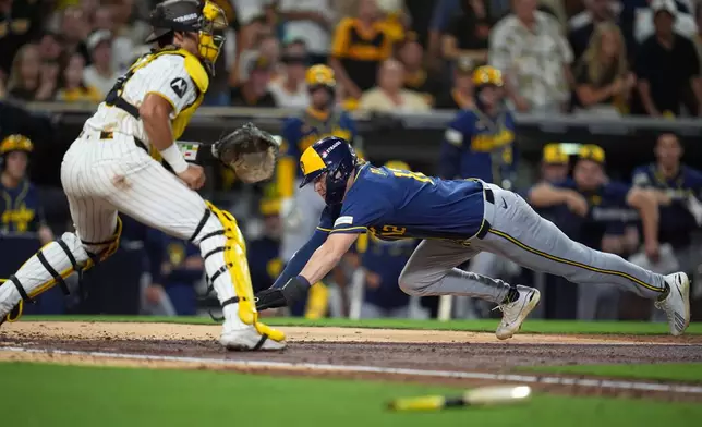 Milwaukee Brewers' Cooper Pratt, right, scores past San Diego Padres catcher Ethan Salas during the fifth inning in Game 3 of baseball's National League Division Series Tuesday, Oct. 6, 2026, in San Diego. (AP Photo/Gregory Bull)