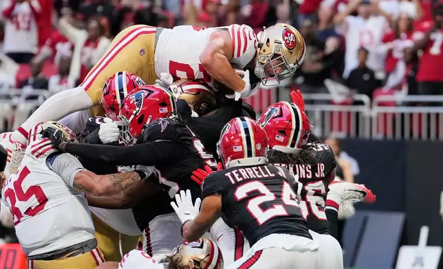 San Francisco 49ers running back Christian McCaffrey, top, leaps into the end zone over Atlanta Falcons' A.J. Terrell Jr. (24), Harold Perkins Jr. (56) and other defenders to score a touchdown during the first half of an NFL football game in Atlanta, Sunday, Oct. 25, 2026. (AP Photo/Brynn Anderson)