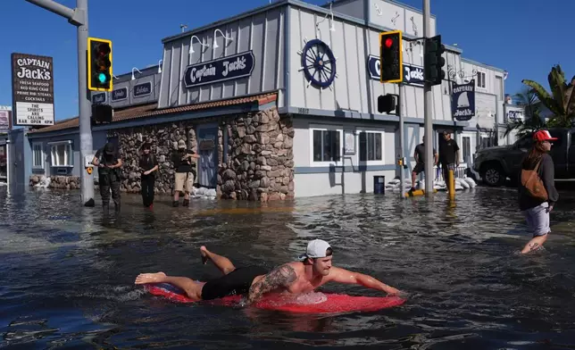 A man surfs through floodwaters in Huntington Beach, Calif., Wednesday, Oct. 28, 2026. (AP Photo/Jae C. Hong)
