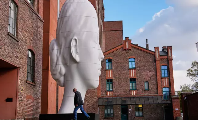 A visitor enters the Kueppersmuehle Museum past a large artwork by Spanish sculptor Jaume Plensa in Duisburg, Germany, Wednesday, Oct. 28, 2026. (AP Photo/Martin Meissner)