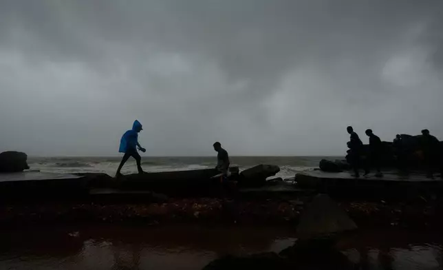 People walk on a damaged road near the shore in Uppada, Kakinada, India, Wednesday, Oct. 28, 2026, after Cyclone Arnab crossed the Andhra Pradesh coast earlier in the day. (AP Photo/Mahesh Kumar A.)