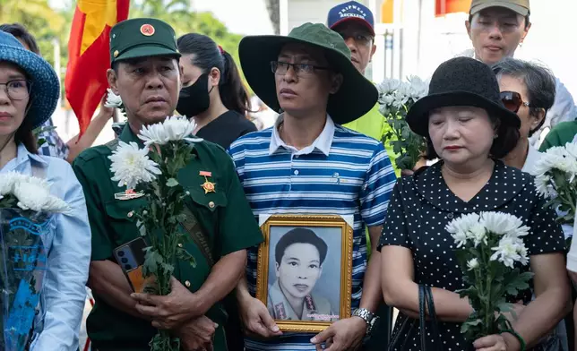 People watch as 731 sets of martyrs' remains found at Le Thi Rieng Cultural Park are transferred for burial at Ho Chi Minh City Martyrs' Cemetery Wednesday, Oct. 14, 2026, in Ho Chi Minh City, Vietnam. (AP Photo/Thanh Hue)