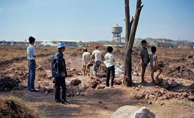 FILE- Gravediggers fill the third communal mass grave at a cemetery in Saigon, Vietnam on Feb. 12, 1968. The remains of more than 700 people, believed killed during the 1968 Tet Offensive were laid to rest in Ho Chi Minh City on Wednesday, Oct. 14, 2026, nearly six decades later. This wartime photograph provided a crucial clue, helping researchers locate the mass graves. (AP Photo/Gautron, File)