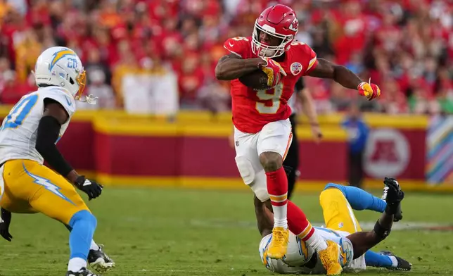 Kansas City Chiefs running back Kenneth Walker III (9) escapes a tackle attempt by Los Angeles Chargers linebacker Del'shawn Phillips, bottom, as Cam Hart (20) moves in to make this stop during the second half of an NFL football game in Kansas City, Mo., Sunday, Oct. 18, 2026. (AP Photo/Ed Zurga)
