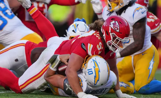 Kansas City Chiefs defensive end Ashton Gillotte (97) lands on top of Los Angeles Chargers quarterback Justin Herbert (10) at the end of a rushing play during the second half of an NFL football game in Kansas City, Mo., Sunday, Oct. 18, 2026. (AP Photo/Charlie Riedel)