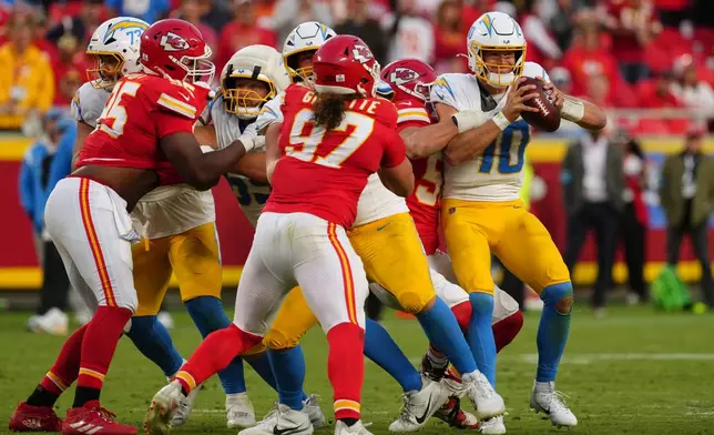 Los Angeles Chargers quarterback Justin Herbert (10) is sacked by Kansas City Chiefs defensive end George Karlaftis, second from right, during the second half of an NFL football game in Kansas City, Mo., Sunday, Oct. 18, 2026. (AP Photo/Ed Zurga)