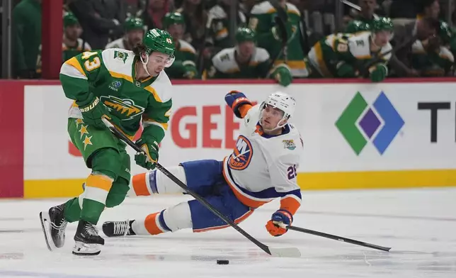 Minnesota Wild defenseman Quinn Hughes (43) controls the puck as New York Islanders right wing Mitchell Chaffee, back, defends during the second period of an NHL hockey game, Thursday, Oct. 29, 2026, in St. Paul, Minn. (AP Photo/Abbie Parr)