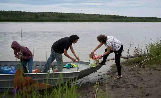 Members of the Woods family unload food and other supplies from their boat after arriving in Rampart, Alaska, from Fairbanks, Friday, July 10, 2026. (AP Photo/Annika Hammerschlag)