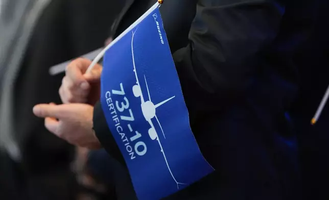 A person holds a flag celebrating the announcement of the certification of Boeing's 737 Max 10 aircraft Tuesday, Oct. 20, 2026, at Boeing's factory in Everett, Wash. (AP Photo/Lindsey Wasson)