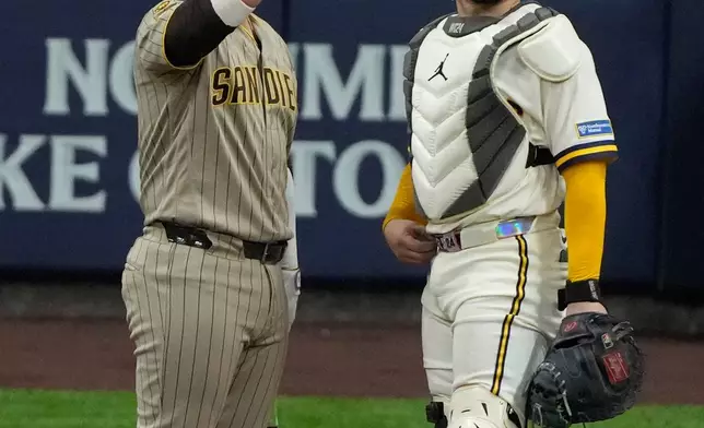 San Diego Padres' Ty France talks to Milwaukee Brewers' William Contreras about hitting a cable near the roof during the ninth inning of Game 1 of a National League Divisional baseball playoff series Sunday, Oct. 4, 2026, in Milwaukee. (AP Photo/Chris Carlson)