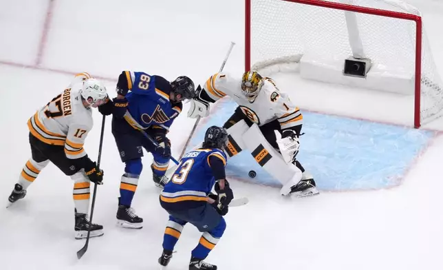 St. Louis Blues' Jake Neighbours (63) scores past Boston Bruins goaltender Jeremy Swayman (1) as Blues' Mason McTavish (83) and Bruins' Will Borgen (17) watch during the third period of an NHL hockey game Thursday, Oct. 29, 2026, in St. Louis. (AP Photo/Jeff Roberson)