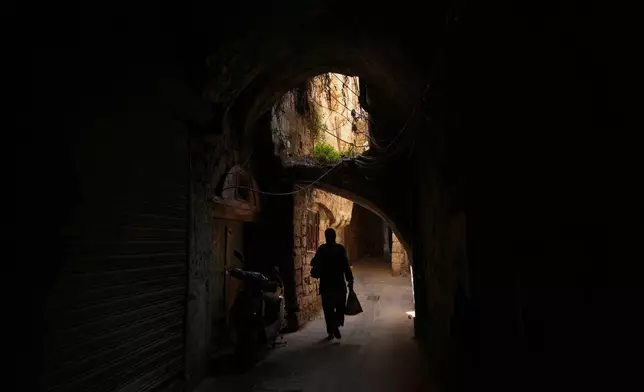 A woman carrying bags walks beneath a stone archway in the Jewish Quarter in the old city of Sidon, southern Lebanon, Friday, Sept. 25, 2026. (AP Photo/Hassan Ammar)