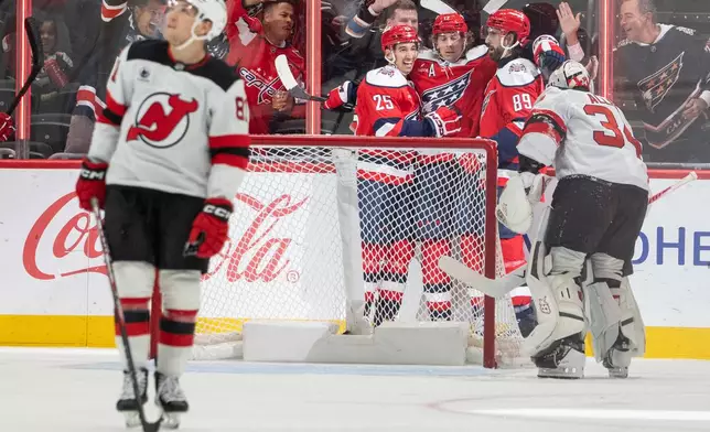 Washington Capitals' Jordan Kyrou (25), Dylan Strome (17) and Alex Tuch (89) celebrate after Strome scored a goal during the second period of an NHL hockey game against New Jersey Devils, Saturday, Oct. 17, 2026, in Washington. (AP Photo/Nathan Howard)