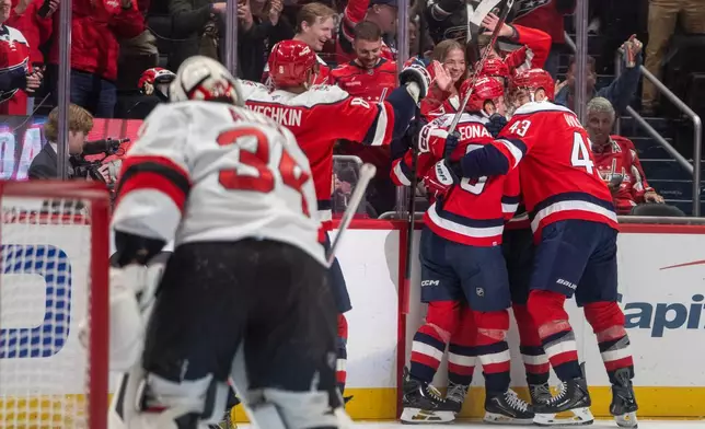 Washington Capitals players celebrate after Ryan Howard (3) scored a goal during the first period of an NHL hockey game against New Jersey Devils, Saturday, Oct. 17, 2026, in Washington. (AP Photo/Nathan Howard)
