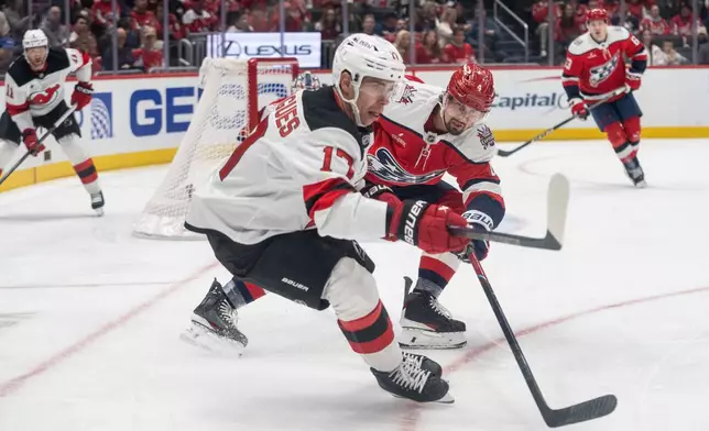 Washington Capitals defenseman Justin Holl (4) stick checks New Jersey Devils center Evan Rodrigues (17) during the second period of an NHL hockey game against New Jersey Devils, Saturday, Oct. 17, 2026, in Washington. (AP Photo/Nathan Howard)