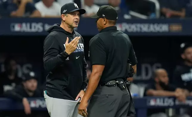New York Yankees manager Aaron Boone, left, talks with home plate umpire Jeremie Rehak after Yankees' Spencer Jones was called out on a fly ball that hit the ceiling of Tropicana Field