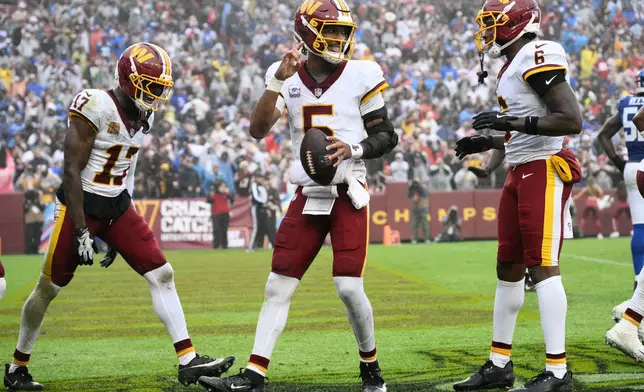Washington Commanders quarterback Jayden Daniels (5) celebrates with teammates Terry McLaurin (17) and Dyami Brown (6) after scoring a touchdown during the second half of an NFL football game against the New York Giants in Landover, Md., Sunday, Oct. 11, 2026. (AP Photo/Nick Wass)