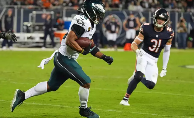 Philadelphia Eagles running back Saquon Barkley, left, runs the ball as Chicago Bears' Dillon Thieneman (31) defends during the second half of an NFL football game in Chicago, Monday, Sept. 28, 2026. (AP Photo/David Banks)