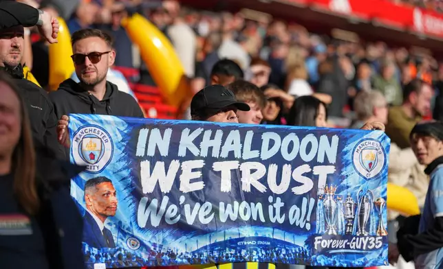 Manchester City supporters hold a banner as they cheer at the stand prior to the English Premier League soccer match between Liverpool and Manchester City in Liverpool, England, Sunday, Oct. 11, 2026. (AP Photo/Jon Super)