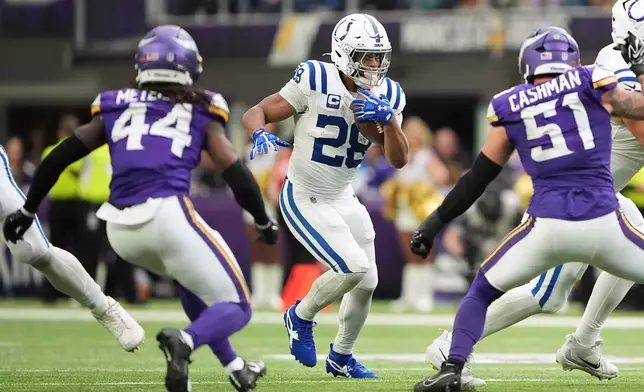 Indianapolis Colts running back Jonathan Taylor (28) runs against Minnesota Vikings safety Josh Metellus (44) and linebacker Blake Cashman (51) during the second half of an NFL football game in Minneapolis, Sunday, Oct. 25, 2026. (AP Photo/Ellen Schmidt)