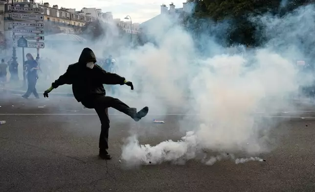 A protesters kicks a teargas canister during scuffles following a demonstration against under-resourced schools, in Paris, Tuesday, Oct. 6, 2026. (AP Photo/Teresa Suarez)