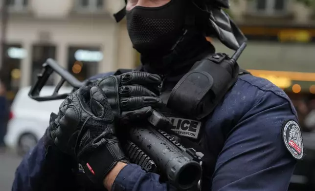 A policeman holds a LBD flash-ball gun as he faces students during a protest against under-resourced schools, in Paris, Wednesday, Oct. 7, 2026. (AP Photo/Thibault Camus)