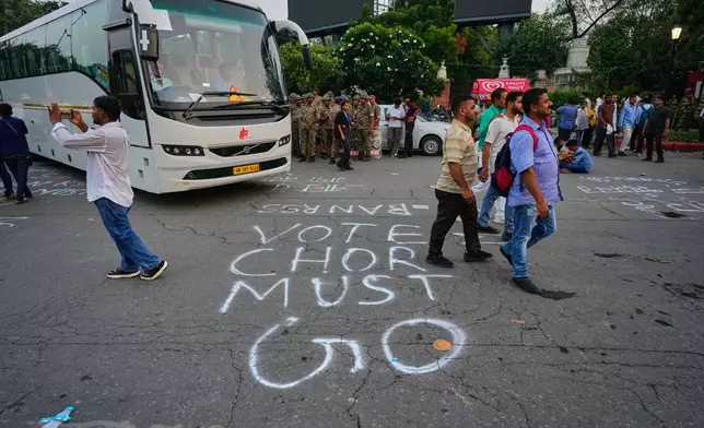 Protesters and commuters walk past graffiti on a road depicting allegations of vote theft during a demonstration demanding the resignation of Chief Election Commissioner Gyanesh Kumar in New Delhi, India, Monday, Oct. 12, 2026. (AP Photo/Manish Swarup)