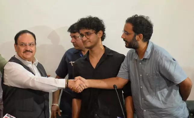FILE -Saurav Das, chief spokesperson of the Cockroach Janta Party, center, looks on as fellow spokesperson Ashutosh Ranka, right, shakes hands with India's Health Minister J.P. Nadda during a joint press conference in New Delhi, India, July 25, 2026, following the resignation of India's education minister. (AP Photo, File)